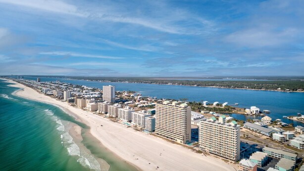 A coastal cityscape with a beachfront hotel area featuring high-rise buildings, a sandy beach, and a clear blue sky. - Crystal Shores W 301 (Gulf Shores)