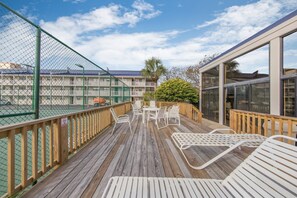 A wooden deck with outdoor seating, a fence, and a building with large windows. - Seaside Beach & Racquet 4311 (Orange Beach)