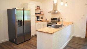 Una cocina moderna con un refrigerador de acero inoxidable, un horno empotrado, un lavamanos y encimeras de madera.