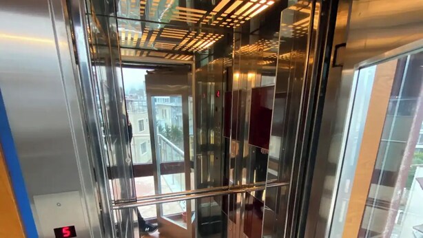 Un ascenseur doté d’un écran numérique affichant le chiffre 5 et d’un bouton situé en dessous.