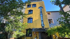 Un bâtiment jaune avec une porte noire et un petit balcon.