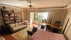 Une chambre confortable avec un lit, un bureau, une chaise, un canapé et une bibliothèque.