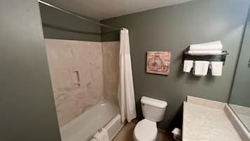 A bathroom with a bathtub, toilet, and a shower curtain.