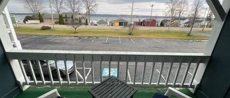Een balkon met uitzicht op een parkeerplaats en huizen aan de overkant van het water.