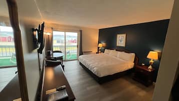 Habitación de hotel con cama, escritorio, silla, televisión y vista al exterior.