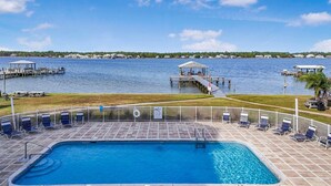 A swimming pool with a view of the water, a dock, and a gazebo. - Lagoon Run 105 (Gulf Shores)