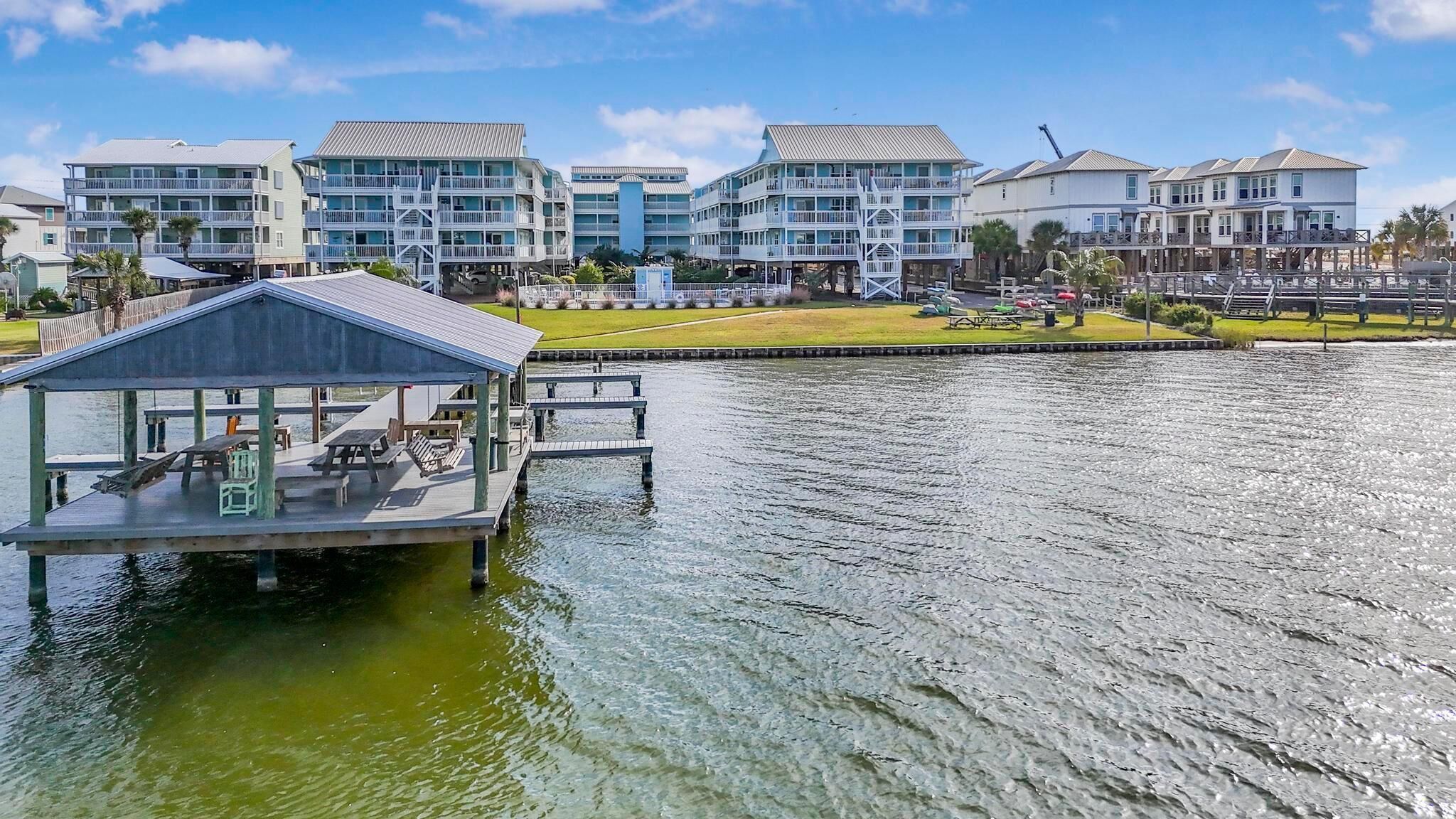 A waterfront property with a dock, multiple-story buildings, and a grassy area.