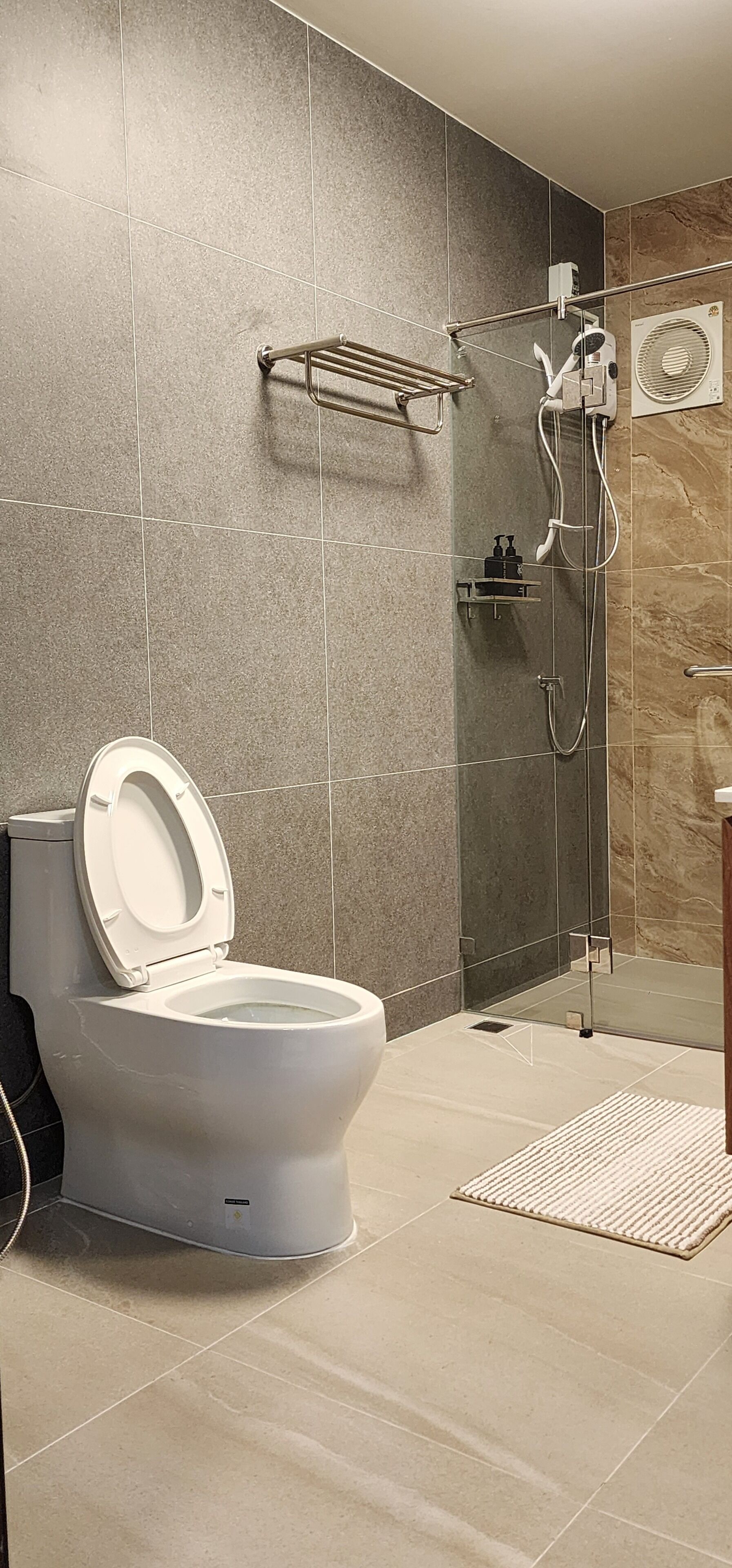 A modern bathroom with a toilet, shower, and a glass-enclosed shower area.