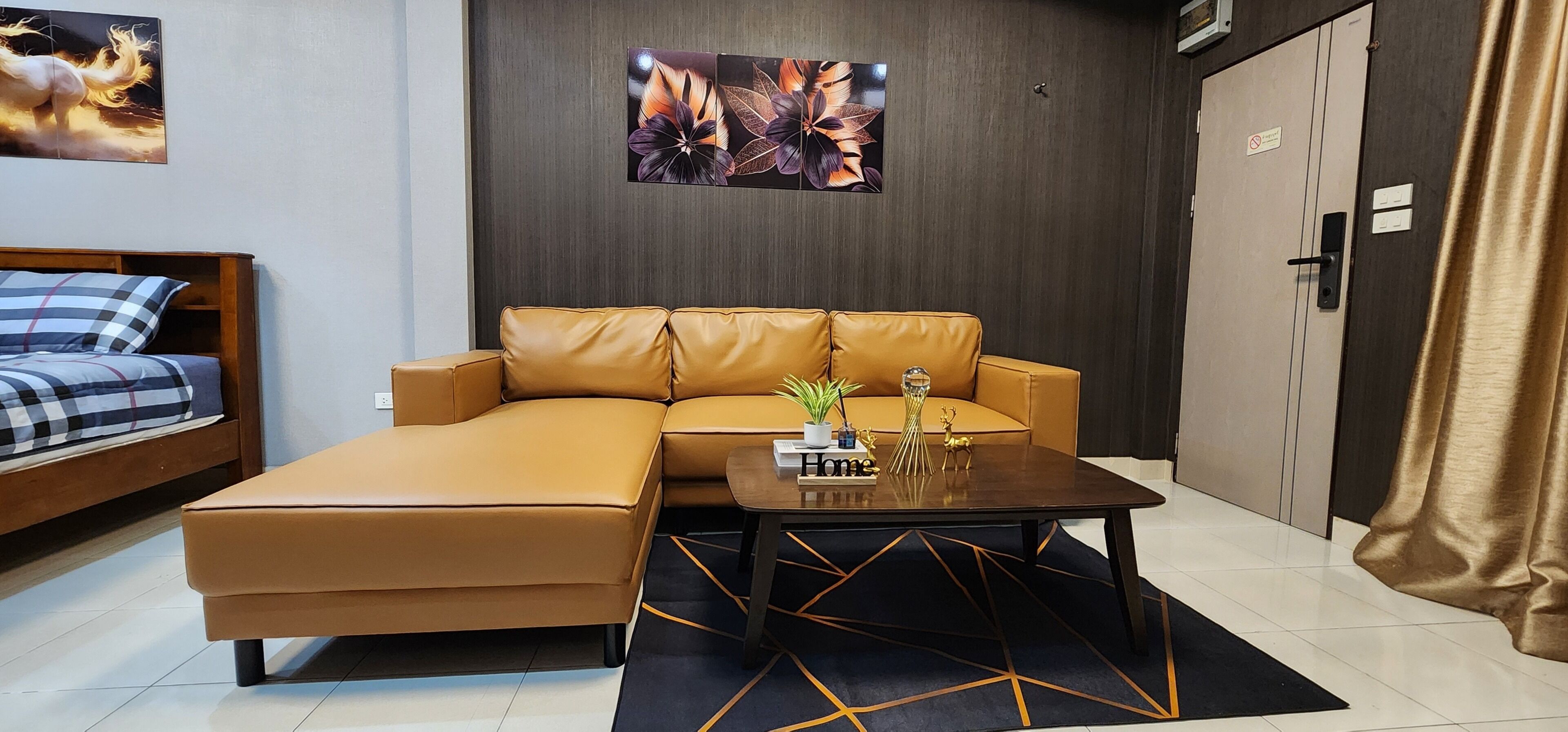 A modern hotel room with a sofa, a small table with a plant, and a bed with a checkered blanket.