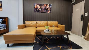 A modern hotel room with a sofa, a small table with a plant, and a bed with a checkered blanket.