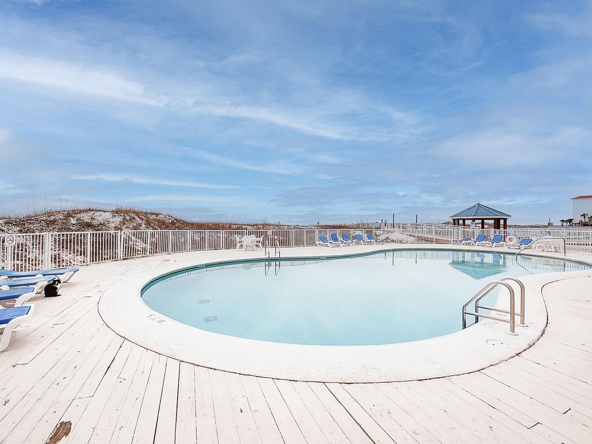 Un espace piscine doté d’une terrasse en bois, de chaises longues et d’un gazebo.