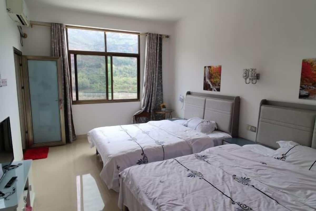 Une chambre d’hôtel avec deux lits, un bureau avec une chaise, une fenêtre avec des rideaux et un radiateur.