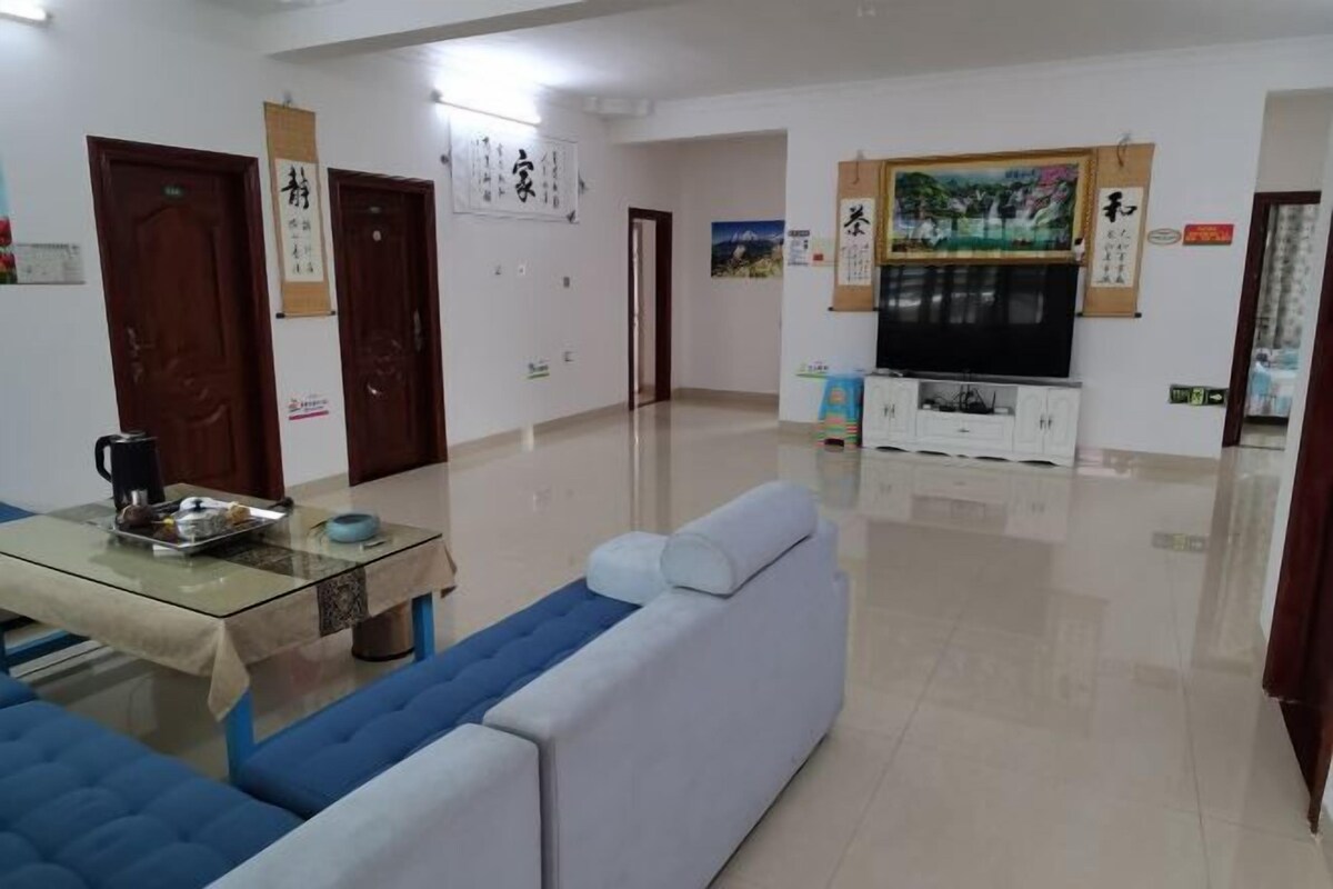 A spacious living room with a sofa, a glass-top coffee table, and a TV stand with cabinets.
