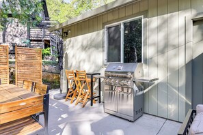 An outdoor kitchen area with a grill, wooden table, and chairs. - Game Room & Patio: Picturesque Home in Sonora (Sonora)