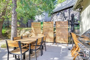 An outdoor patio with a wooden table and chairs, a grill, and a stone wall. - Game Room & Patio: Picturesque Home in Sonora (Sonora)
