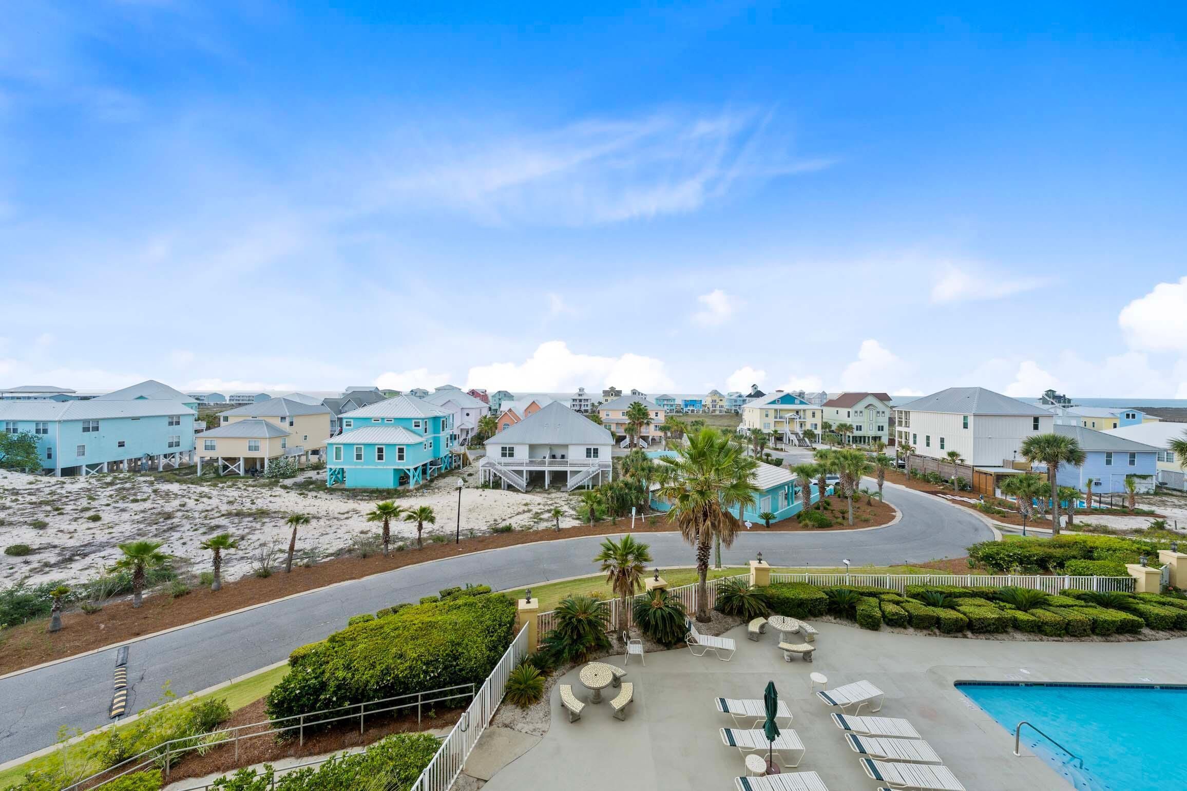 A coastal resort with beachfront villas, a swimming pool, and a curved road.