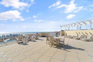 A rooftop terrace with hexagonal tiles, outdoor seating, and a view of the sea. - The Indies 303 (Gulf Shores)