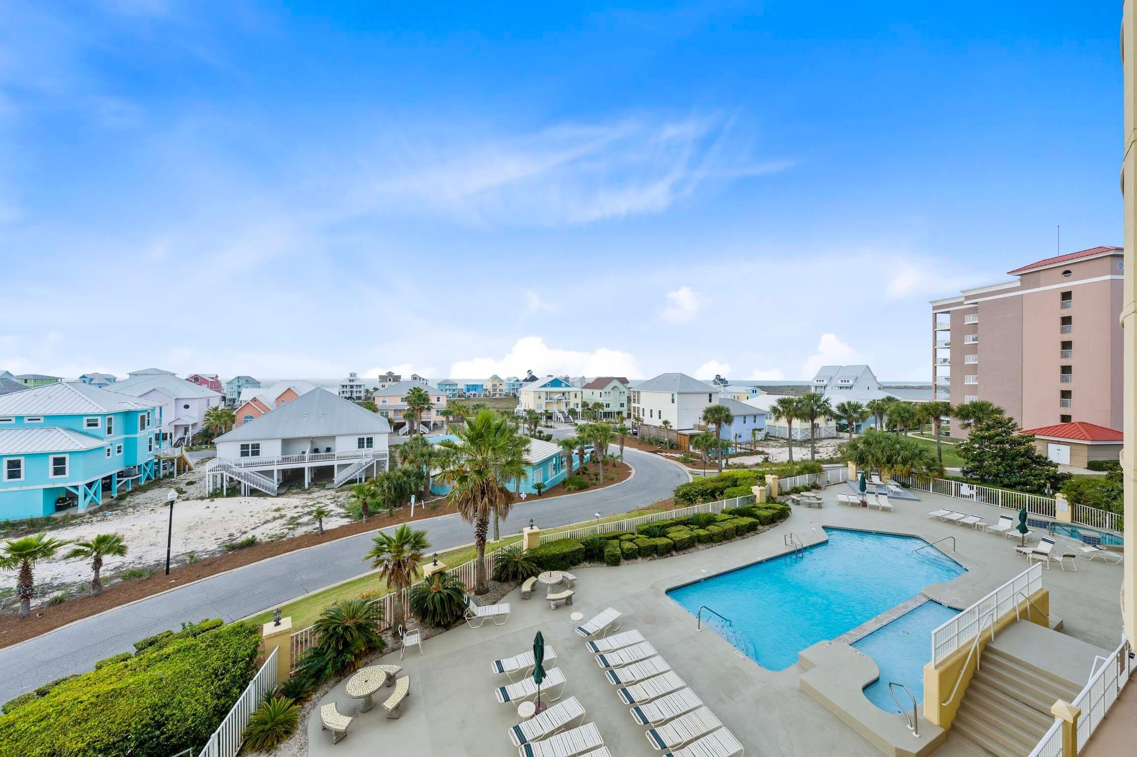 A resort with a swimming pool, lounge chairs, and a view of the surrounding buildings.