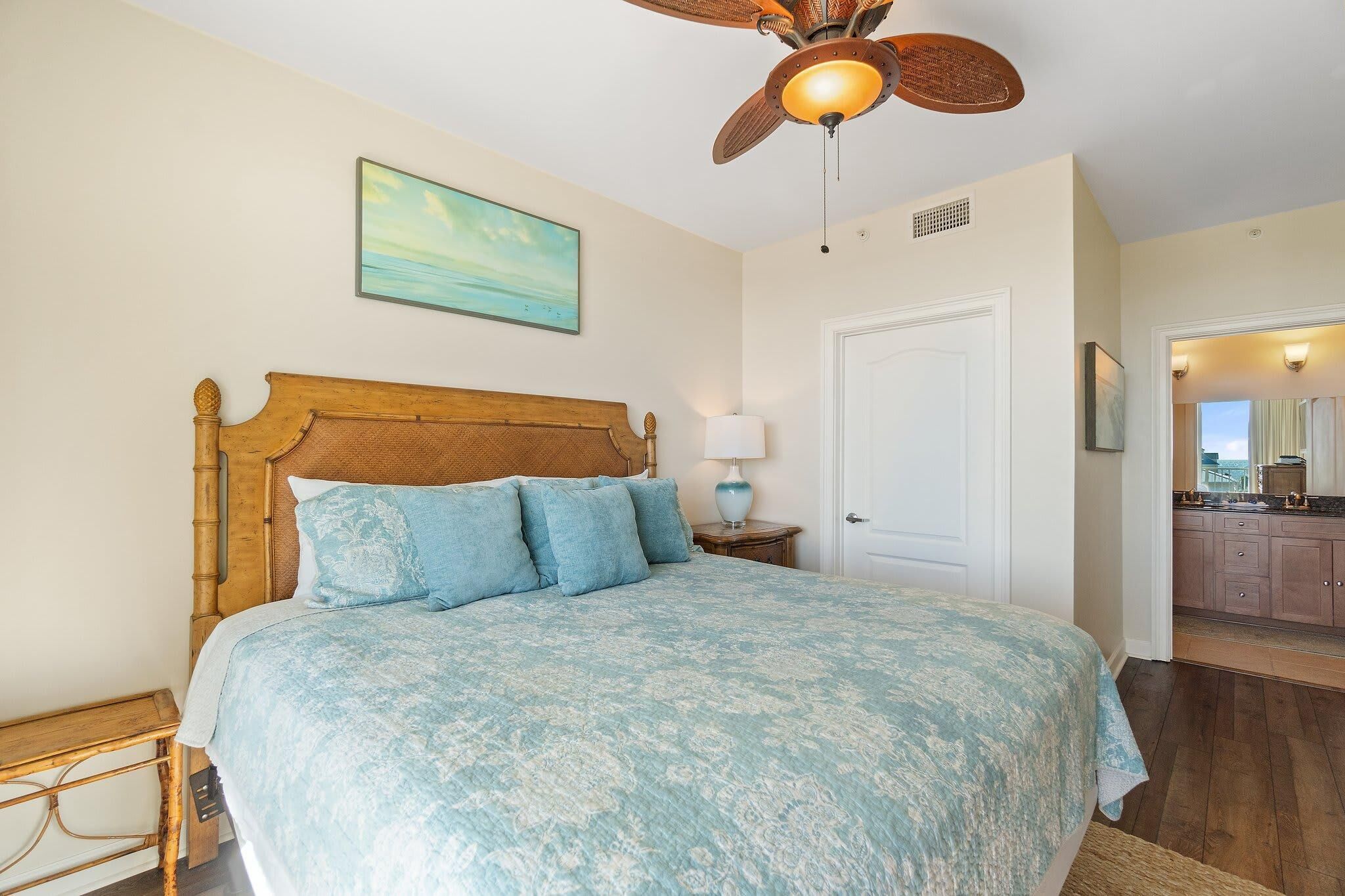 A bedroom with a wooden bed, a ceiling fan, a nightstand, and a painting on the wall.