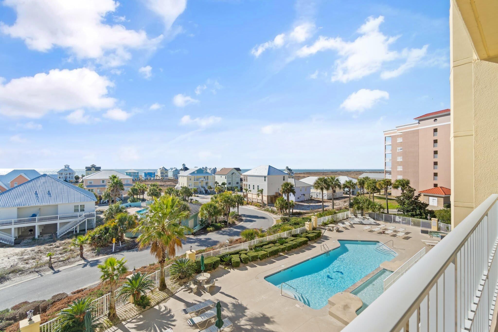 A resort with a swimming pool, palm trees, and beachfront views.