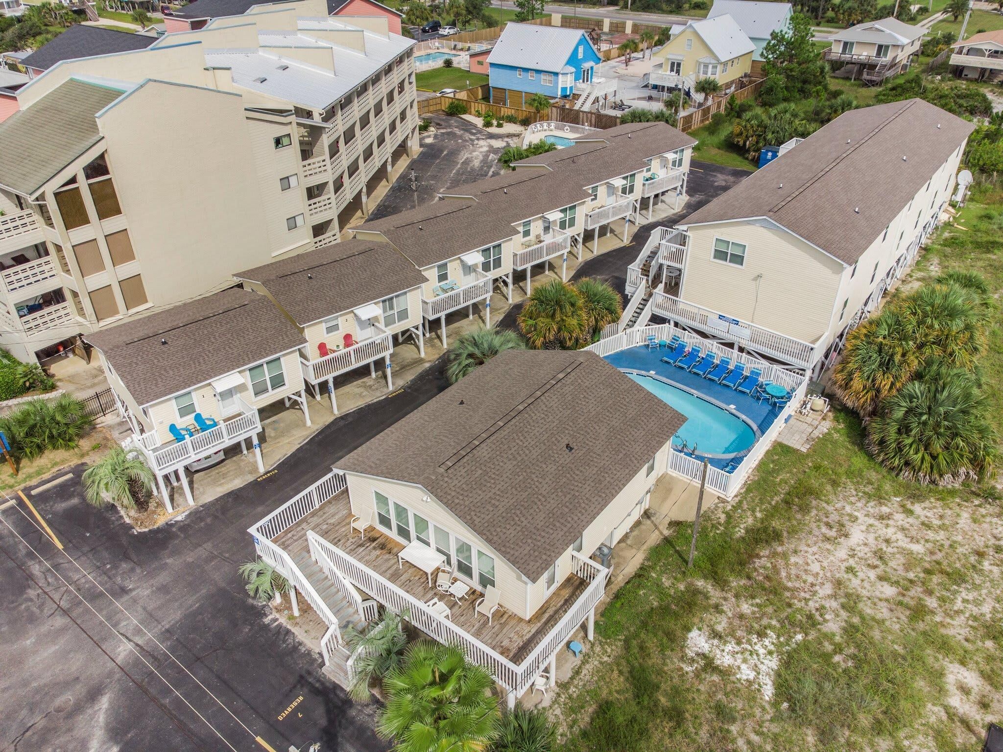 A multi-story hotel with a pool area, balconies, and a beach view.