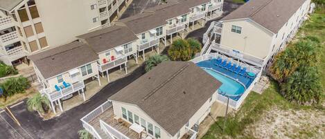 A multi-story hotel with a pool area, balconies, and a beach view.