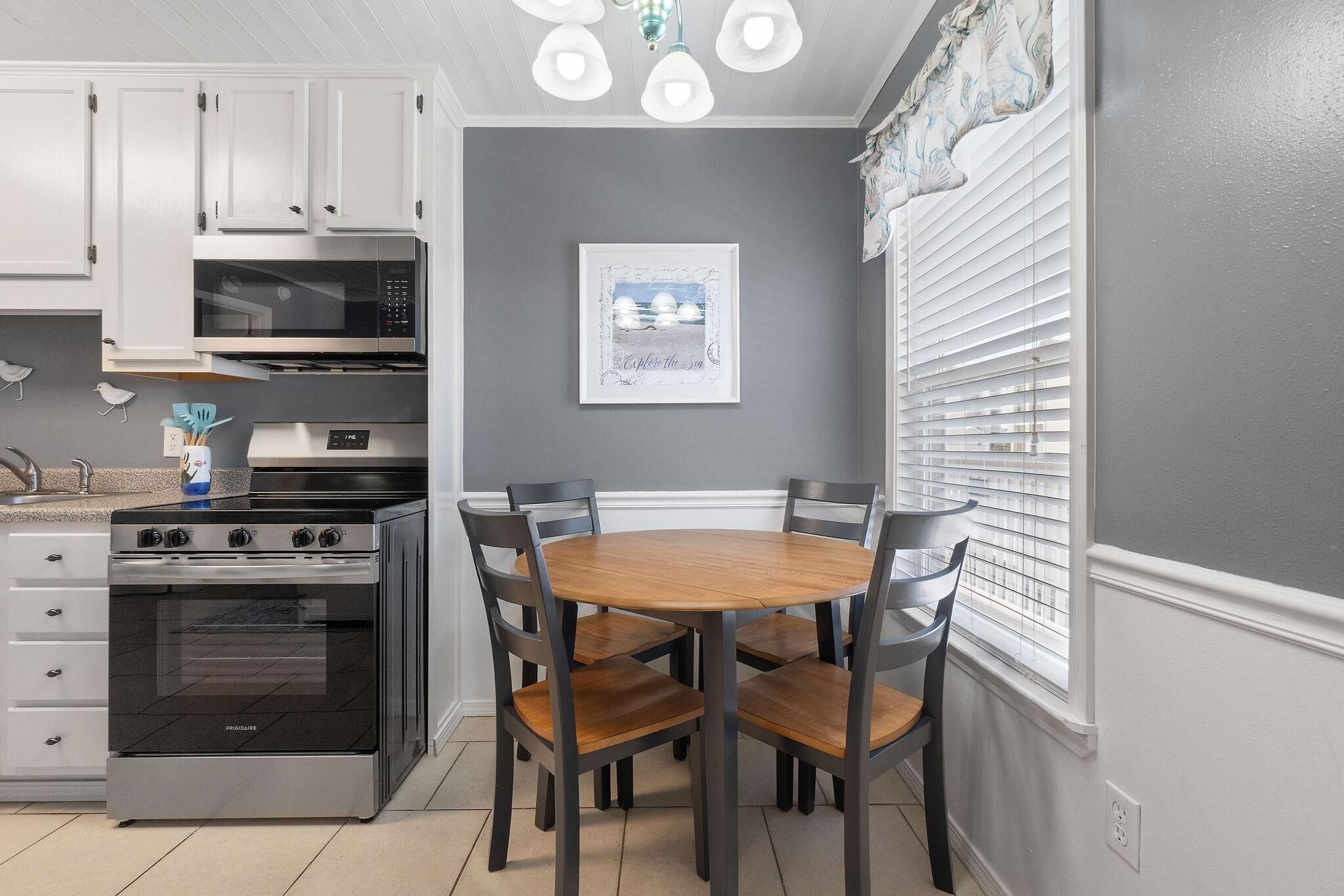 A kitchen with white cabinets, a stainless steel stove, and a wooden dining table with chairs.