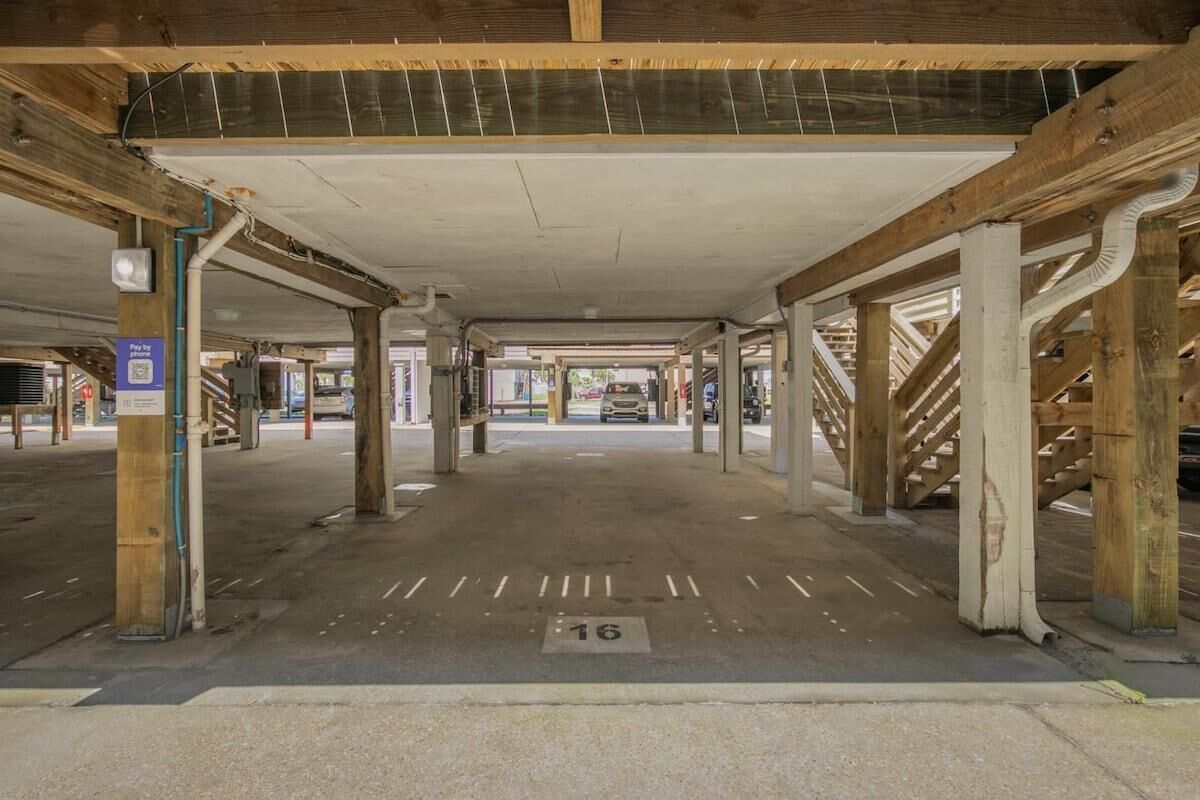 Un parking souterrain avec des piliers en béton, des places de stationnement délimitées et un terminal de paiement par téléphone.