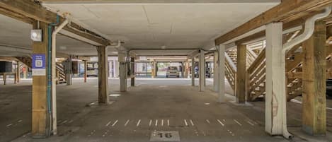 Un parking souterrain avec des piliers en béton, des places de stationnement délimitées et un terminal de paiement par téléphone.