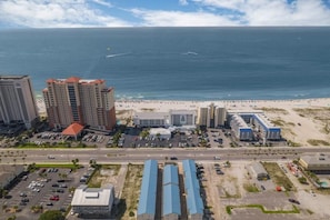 Paisagem costeira com praia, edifícios altos e estacionamento.