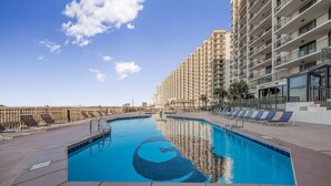 A swimming pool with a 5 ft no diving sign, surrounded by lounge chairs and a high-rise building. - Phoenix Viii 81201 (Orange Beach)