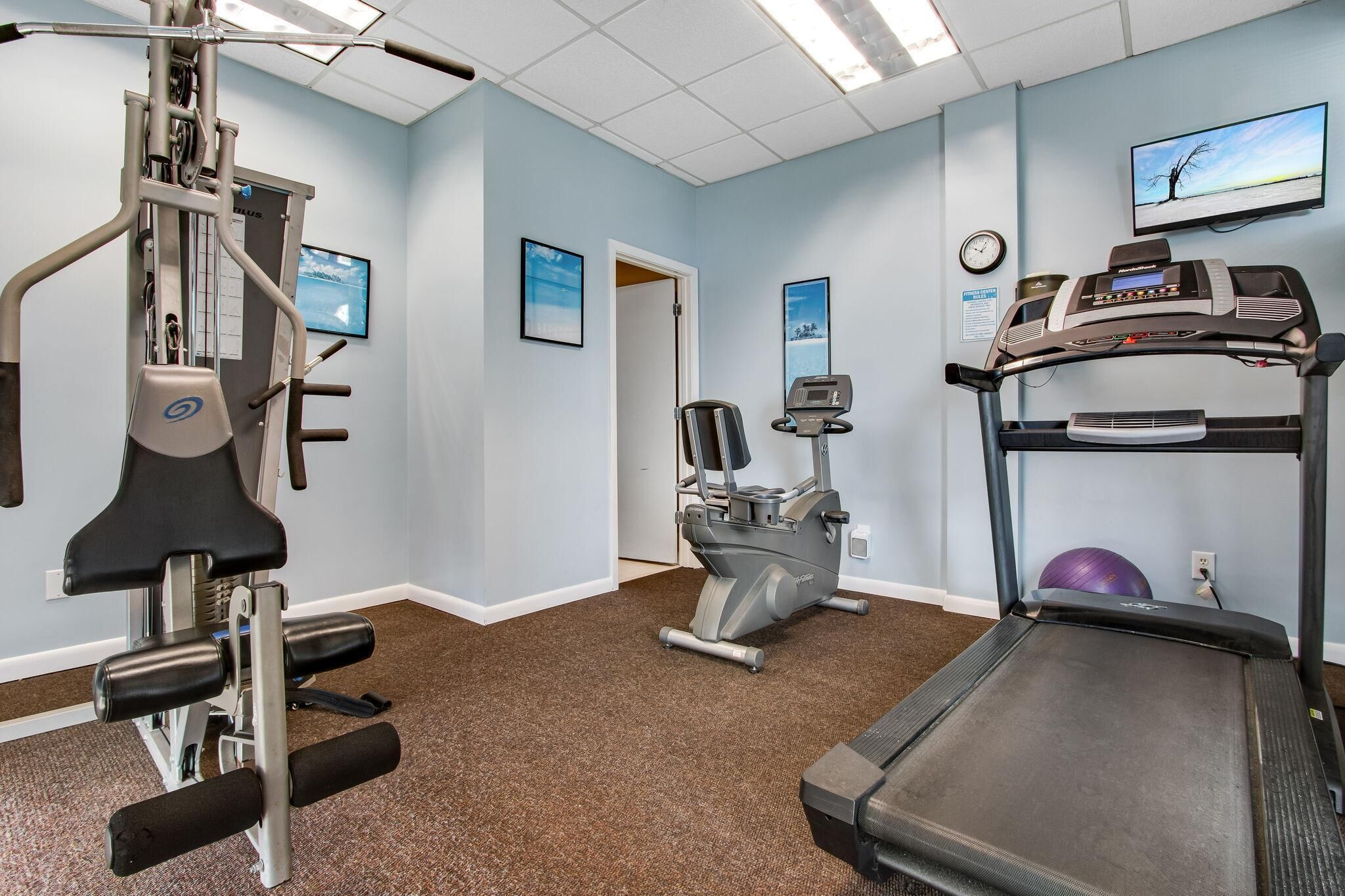 A fitness room with a treadmill, elliptical, and weight machine.