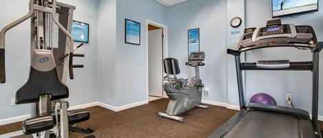 A fitness room with a treadmill, elliptical, and weight machine.