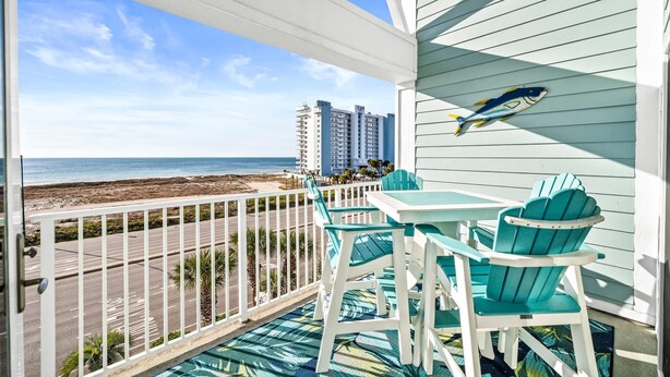 Un balcon avec vue sur la plage et l’océan, comprenant une table et des chaises.