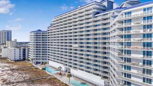 A multi-story hotel with balconies, a pool, and a beach view. - Lighthouse 918 (Gulf Shores)