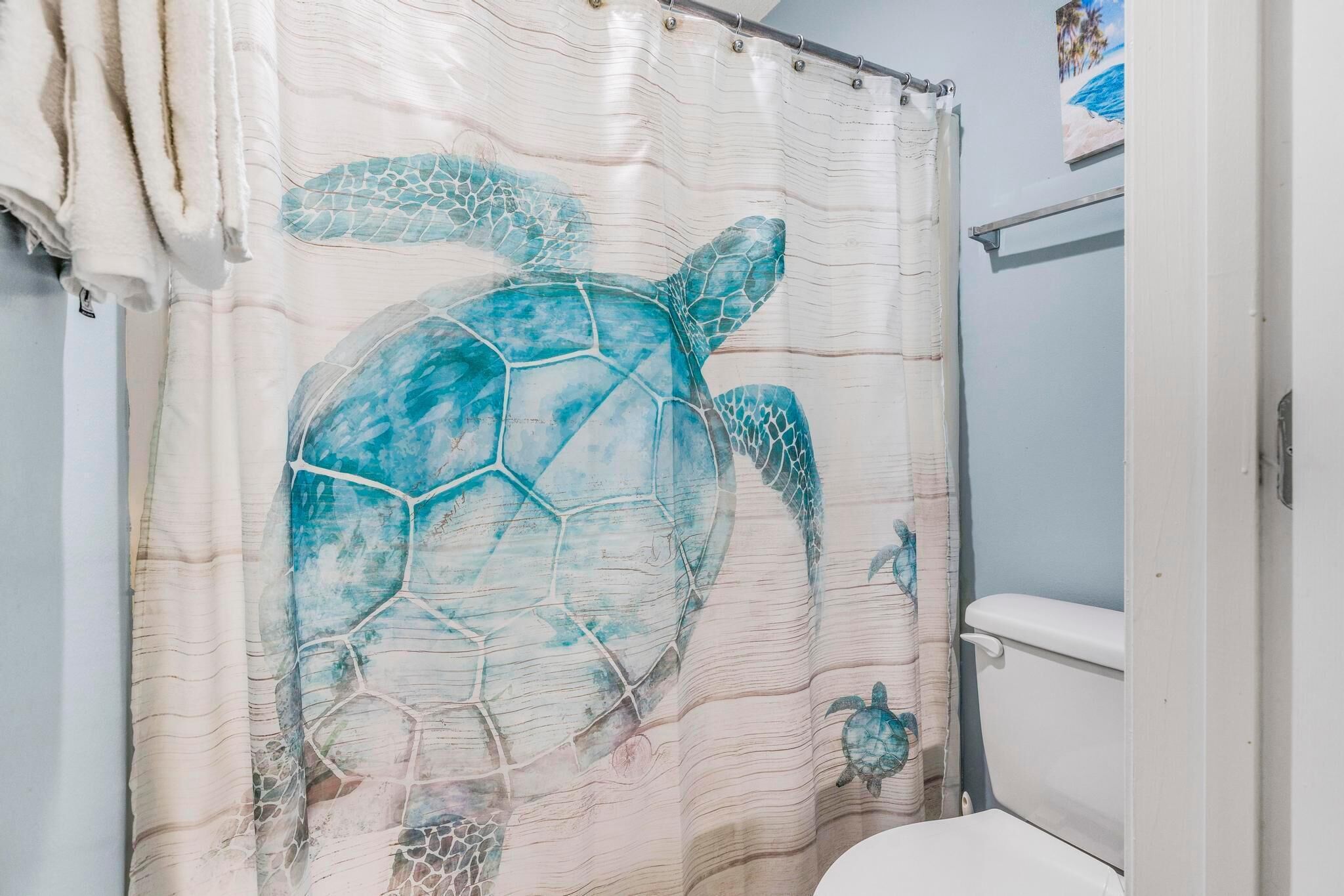 A bathroom with a shower curtain featuring a sea turtle design.