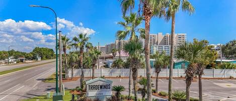 A street view with a sign for 'TRADEWINDS' hotel, a clear sky, and palm trees.