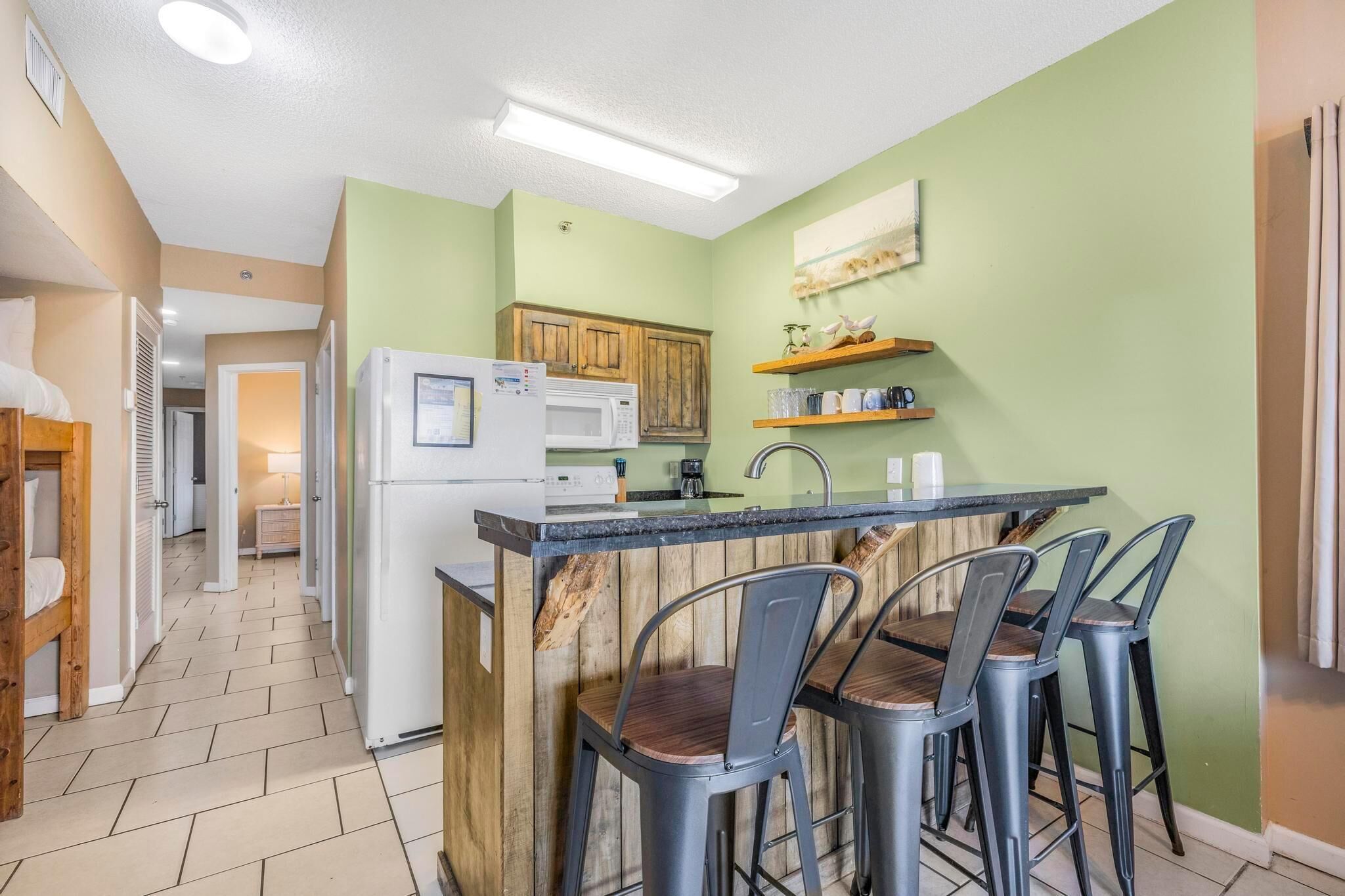 A compact kitchen with a central island, a microwave, and a refrigerator. There are wooden cabinets and a small countertop with a sink.