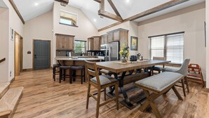 A spacious kitchen with wooden beams, a central island, and a dining area with benches.