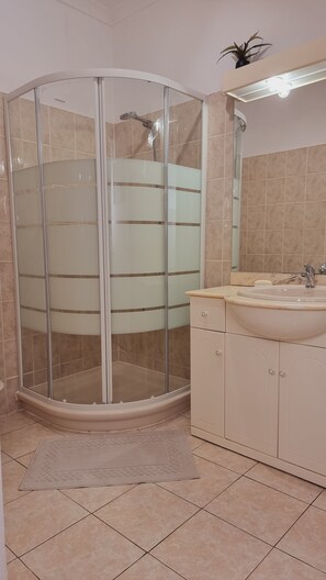Une salle de bain avec une douche à parois de verre, un lavabo et un meuble de rangement.