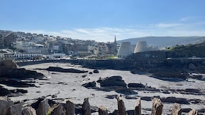 A coastal town with a rocky beach, buildings, and a distinctive modern structure with two large conical towers. - Cosy Apartment Close to Tunnels Beaches (Ilfracombe)
