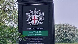 Schild des Epping Forest Besucherzentrums mit Wappen, das Besucher in die Stadt London willkommen heißt.