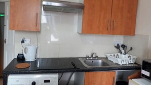 Eine Küche mit Holzschränken, einer Edelstahlspüle, einer Kaffeemaschine und einem Geschirrspüler.