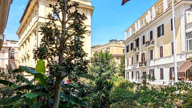 A courtyard with a staircase, a tree, and buildings in the background. - Beautiful 2-bed Apartment in Roma (Rome)