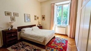 A bedroom with a bed, bedside tables, a radiator, and a window with curtains. - Beautiful 2-bed Apartment in Roma (Rome)