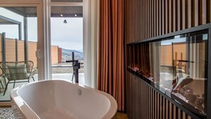 A modern bathroom with a freestanding bathtub, a glass shower enclosure, and a view of a mountainous landscape. - Glacier in Horizon by Yosemite (Midpines)