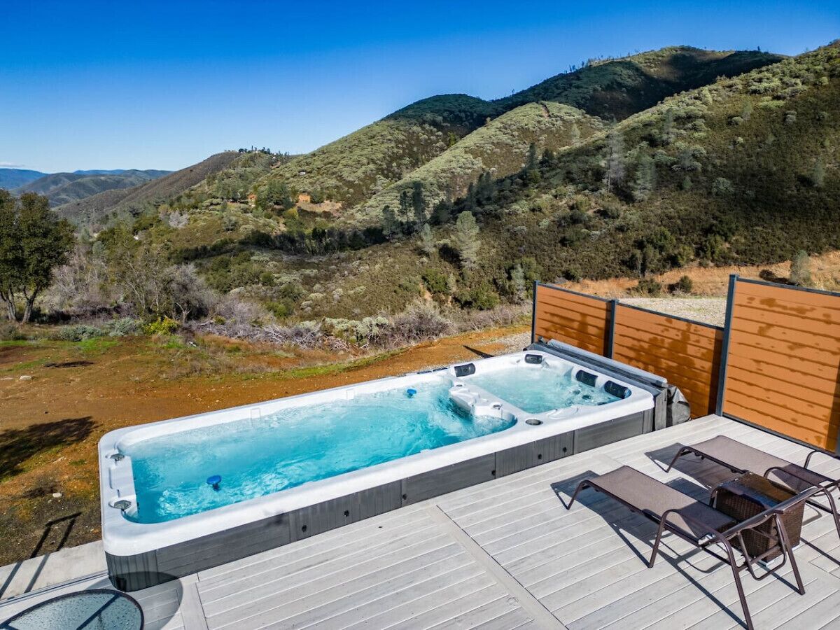 Un jacuzzi en una terraza con vistas a las colinas.