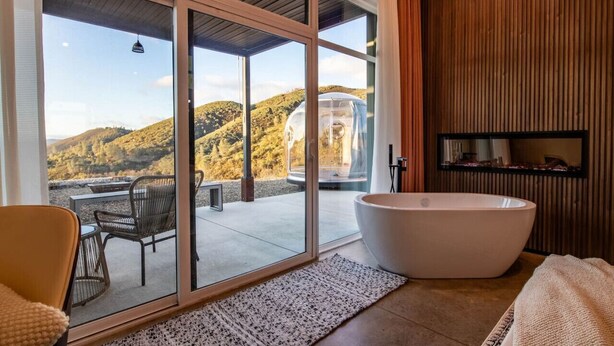 A modern bathroom with a large bathtub, a glass-enclosed shower, and a view of a mountainous landscape. - Glacier in Horizon by Yosemite (Midpines)