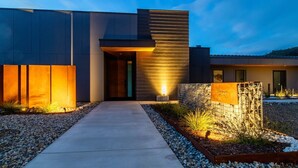 A modern building with a concrete pathway leading to the entrance, a metal fence, and a landscaped area with gravel and plants. - Glacier in Horizon by Yosemite (Midpines)