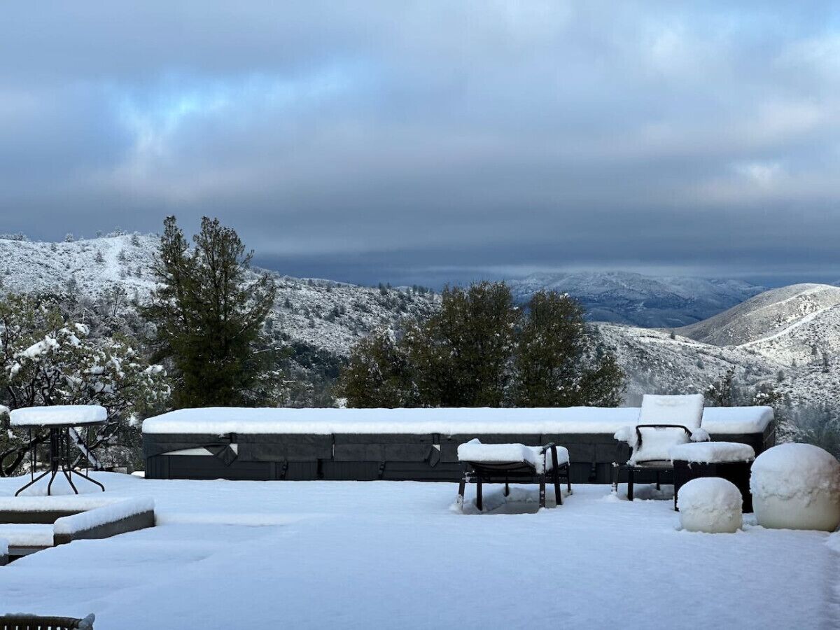 A snow-covered outdoor seating area with a view of snow-covered mountains.